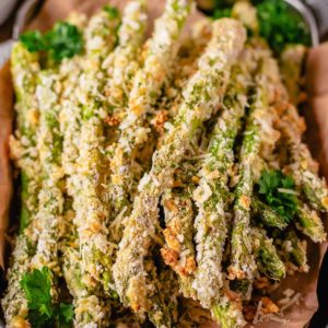 a stack of baked asparagus fries on parchment paper.