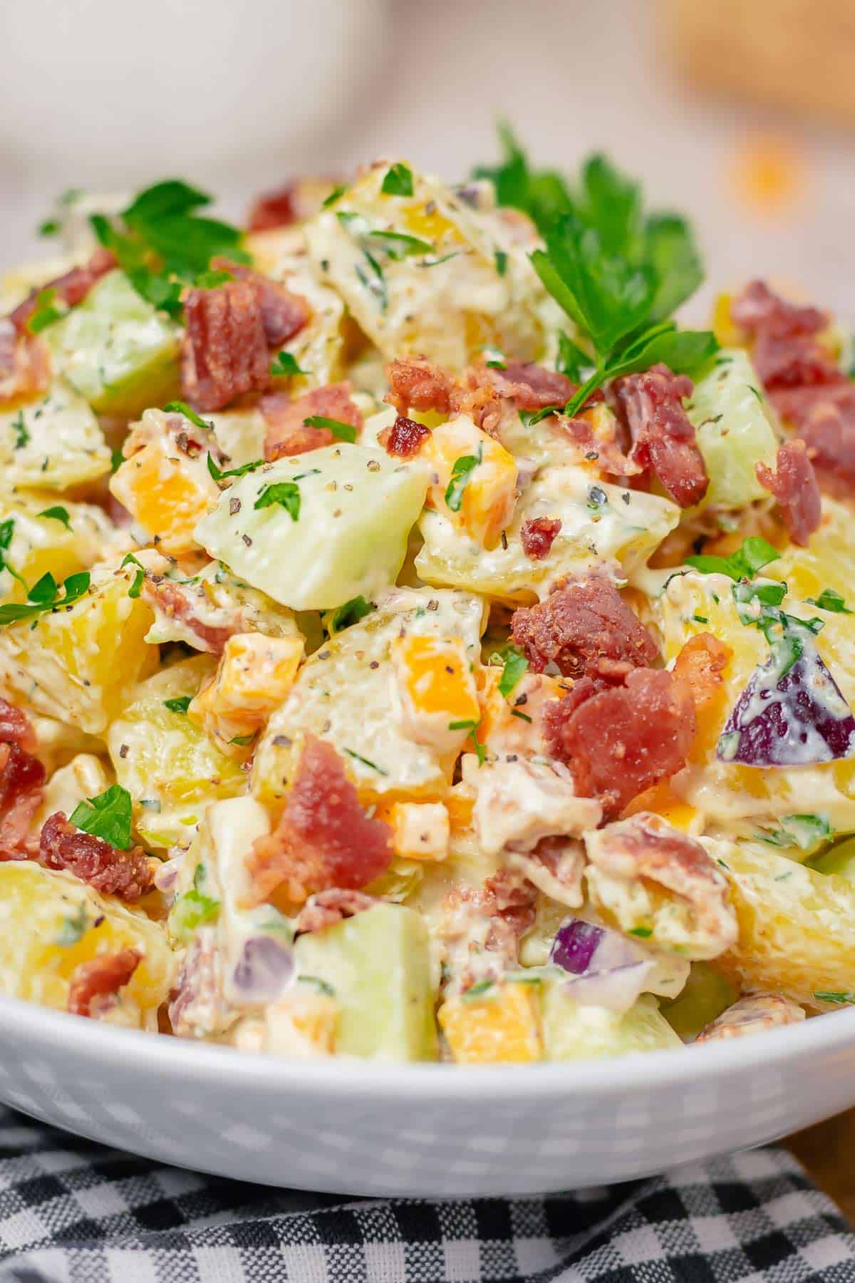 creamy potato salad with cheddar bacon cucumber in ranch dressing in a white bowl