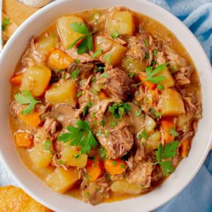 slow cooker beef stew with mushrooms is erved in a white bowl