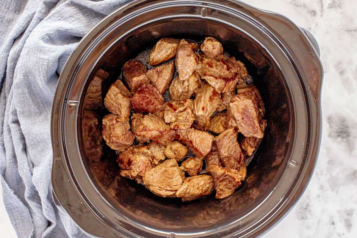 seared beef chunks in a slow cooker