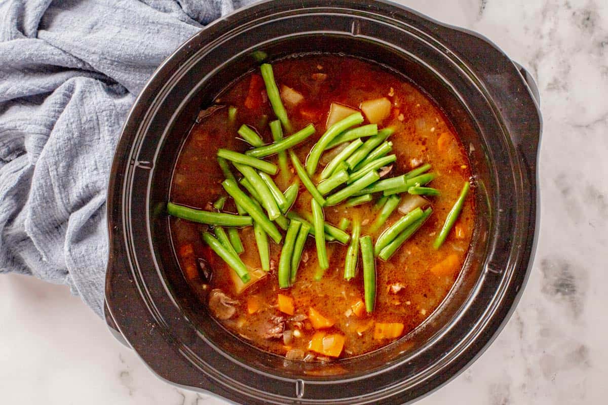 green beans added to slow cooker for beef stew