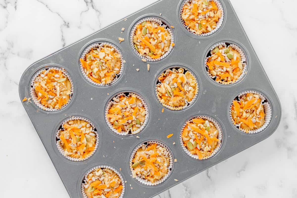 carrot cake muffins batter divided in a 12 muffin tins