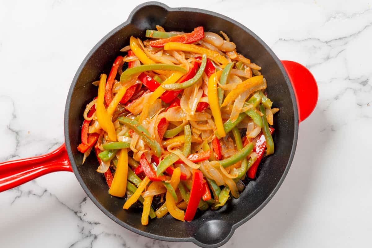 chicken onion and bell peppers cooking in skillet