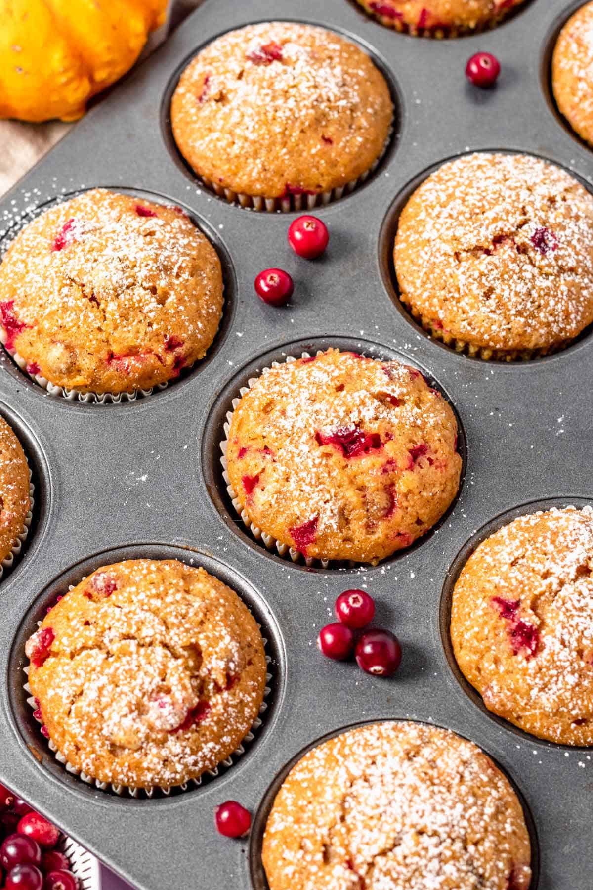 baked pumpkin muffins with cranberries in muffin tin