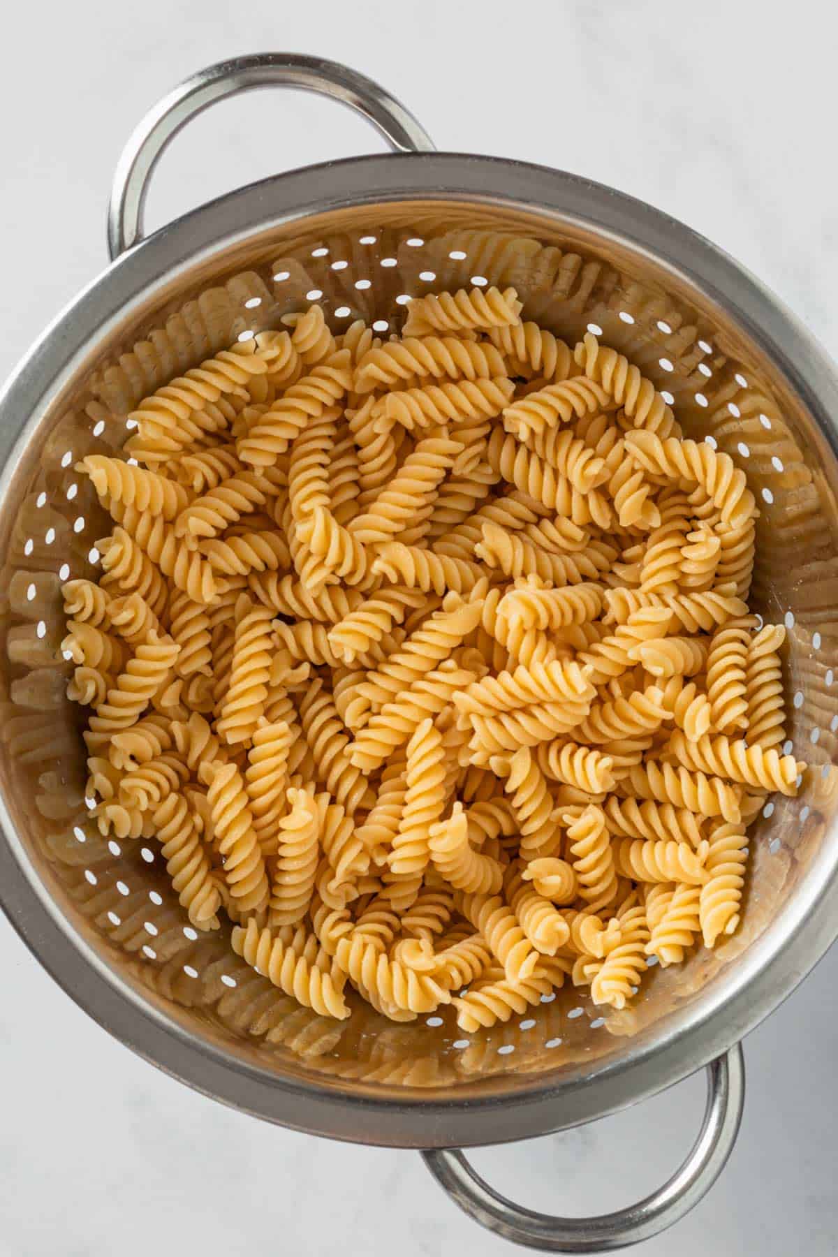 cooked fusilli pasta in colander.