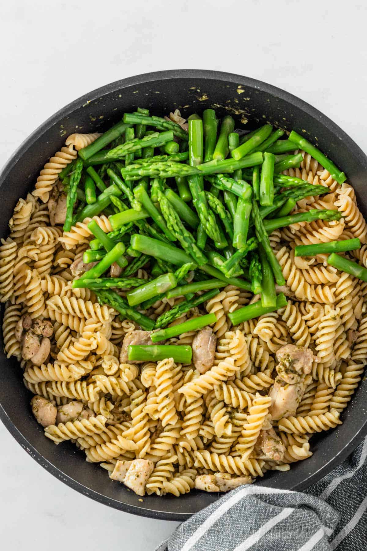 fusilli pasta and asparagus slices in skillet before mixing.