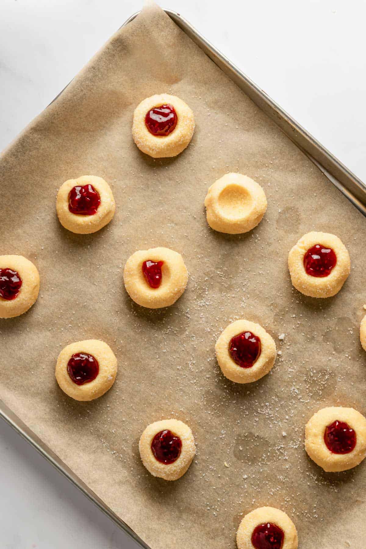 thumbprint cookies with jam on baking sheet