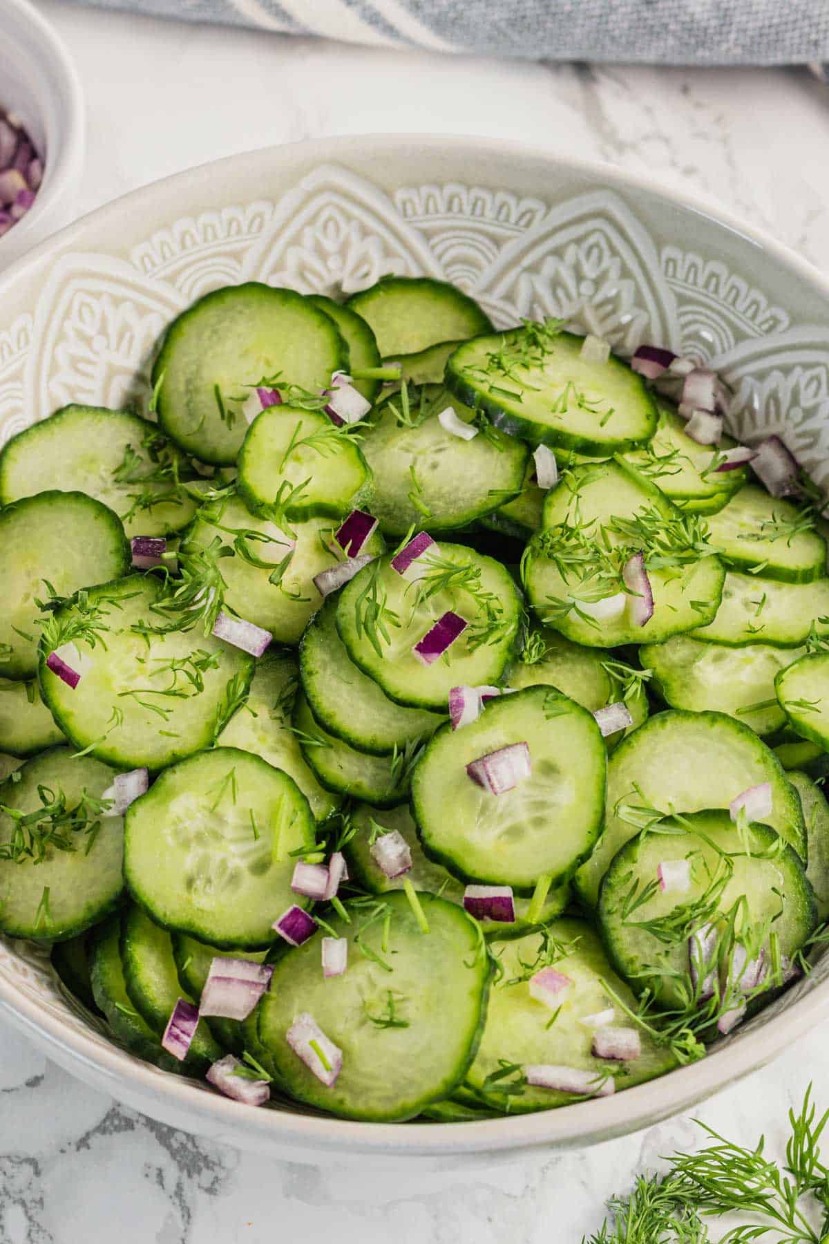 fresh cucumber dill salad in a bowl with red onion and dressing