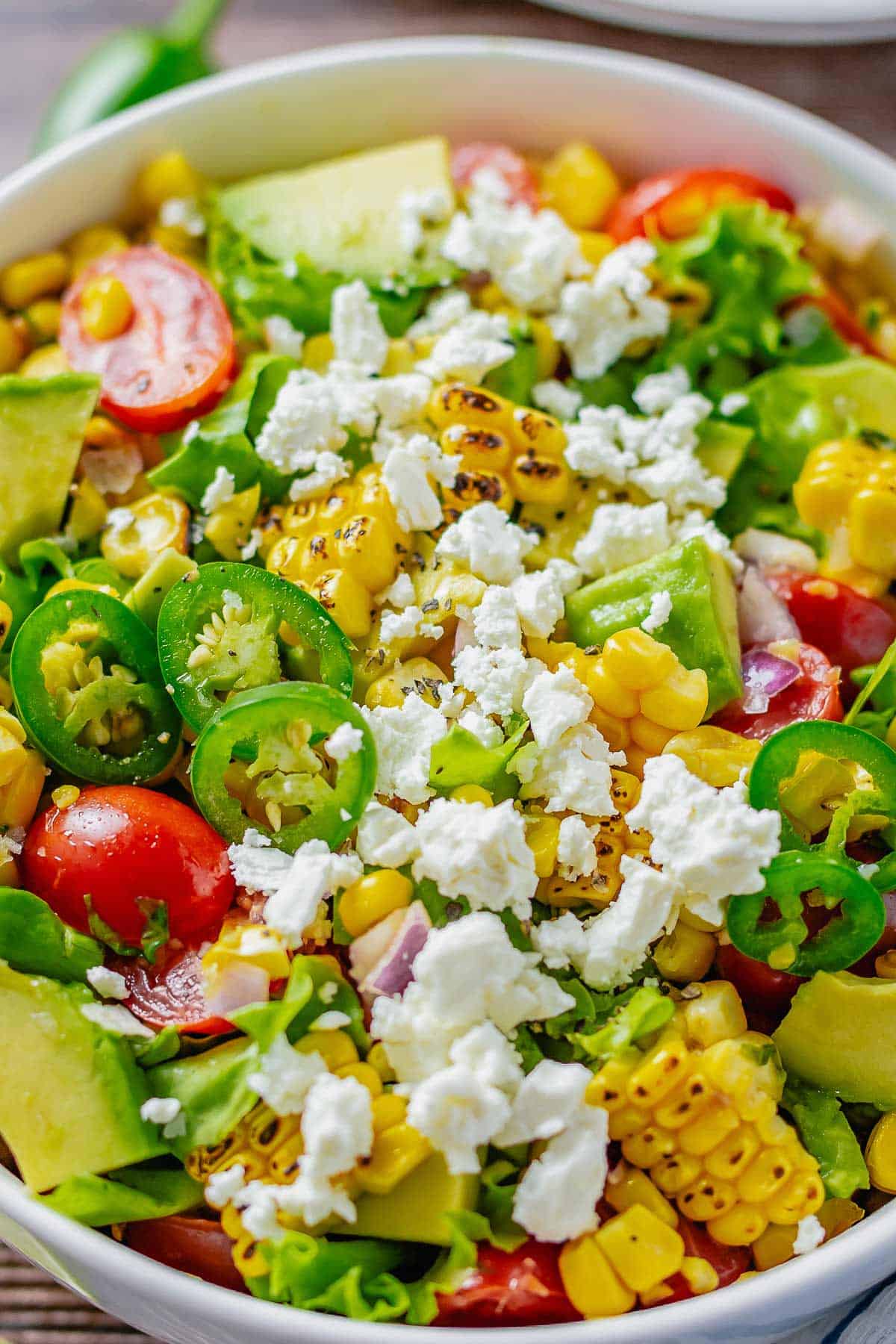avocado corn salad with tomatoes and feta in a bowl.