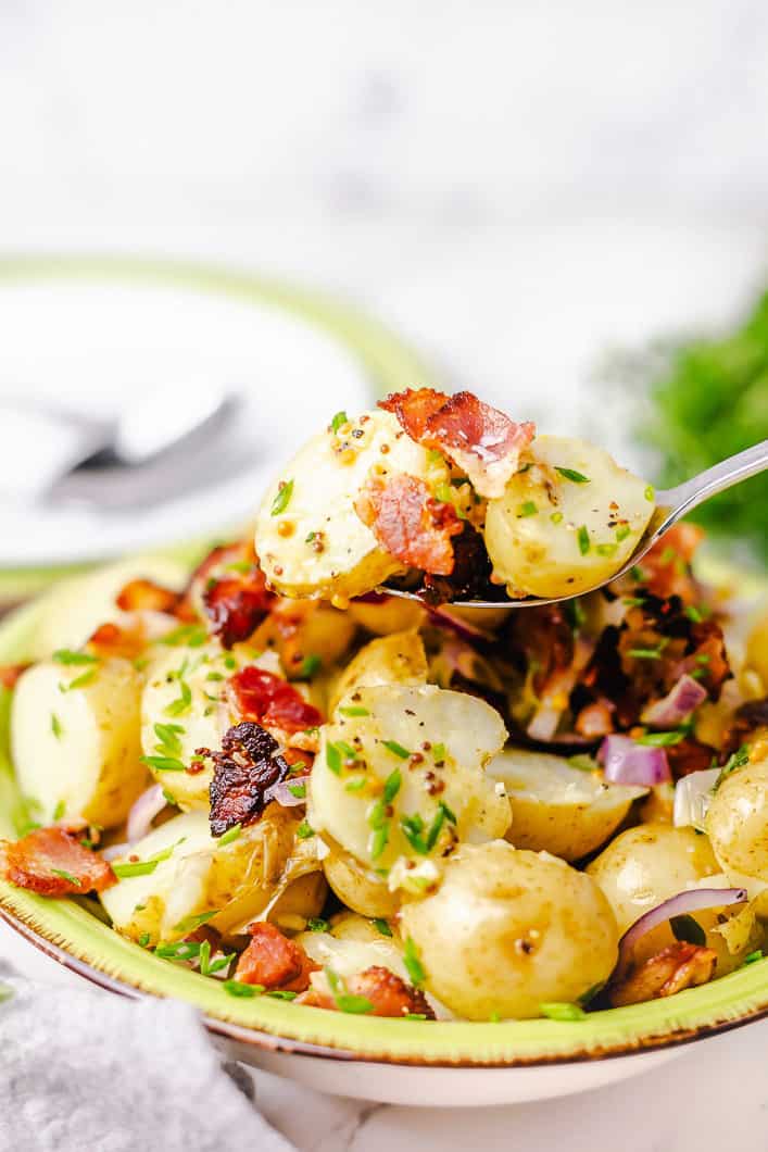 potato salad with bacon and without eggs in a green bowl.
