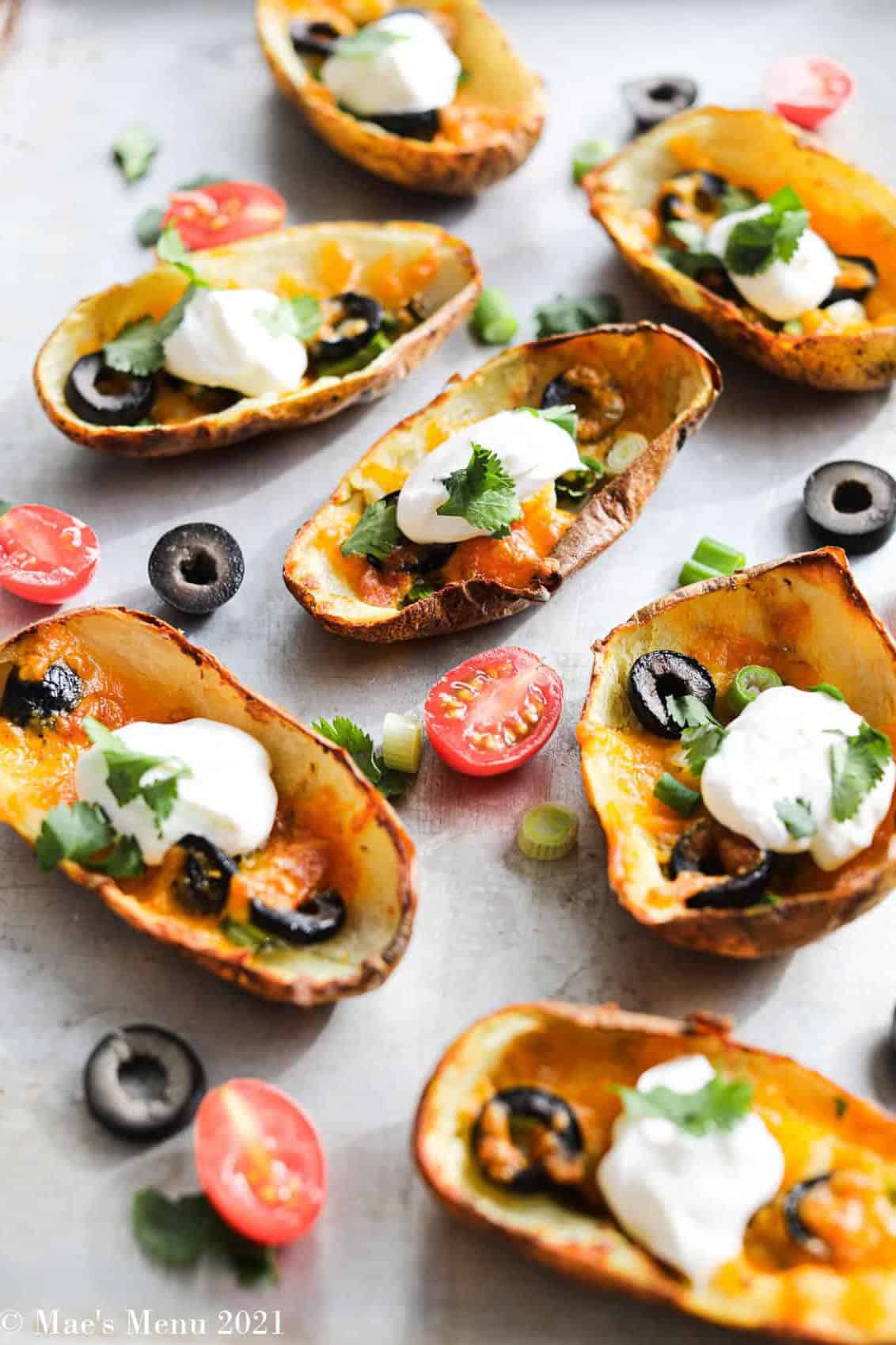 potato skins with olives and sour cream inside scattered on white background