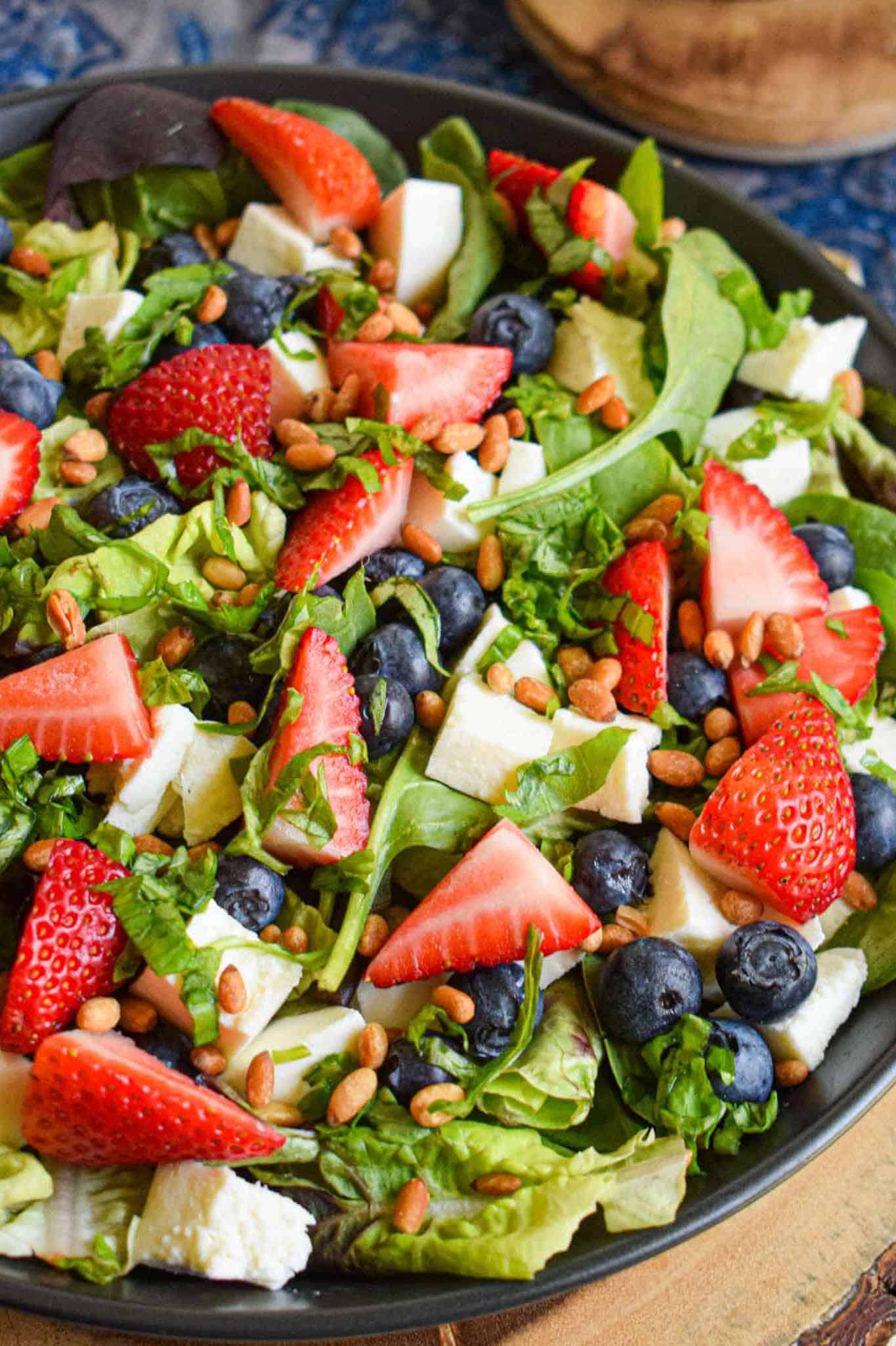 colorful berry salad with strawberries, blueberries and lettuce in a bowl.