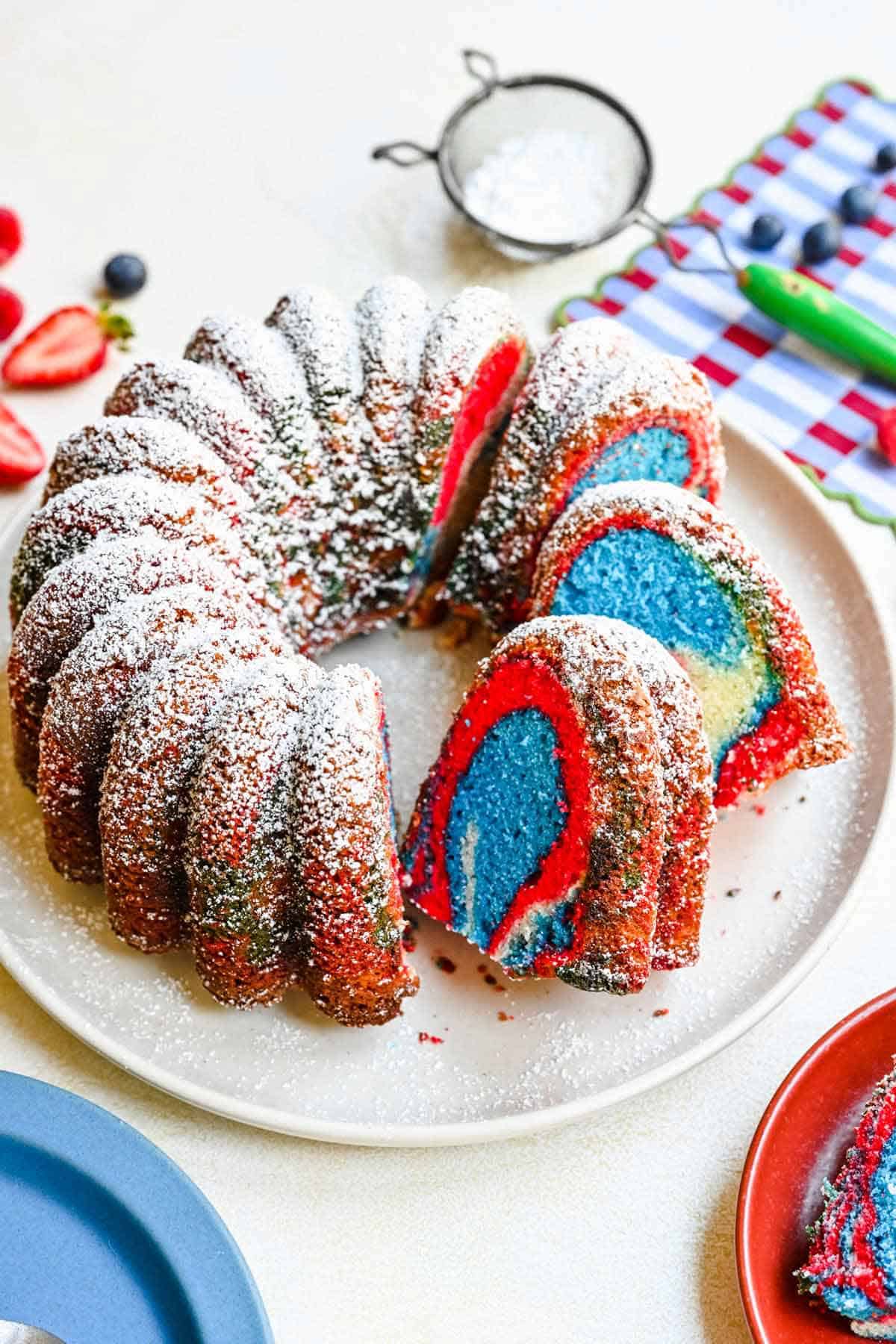 colorful red, white, blue bundt cake with 3 slices cut out.