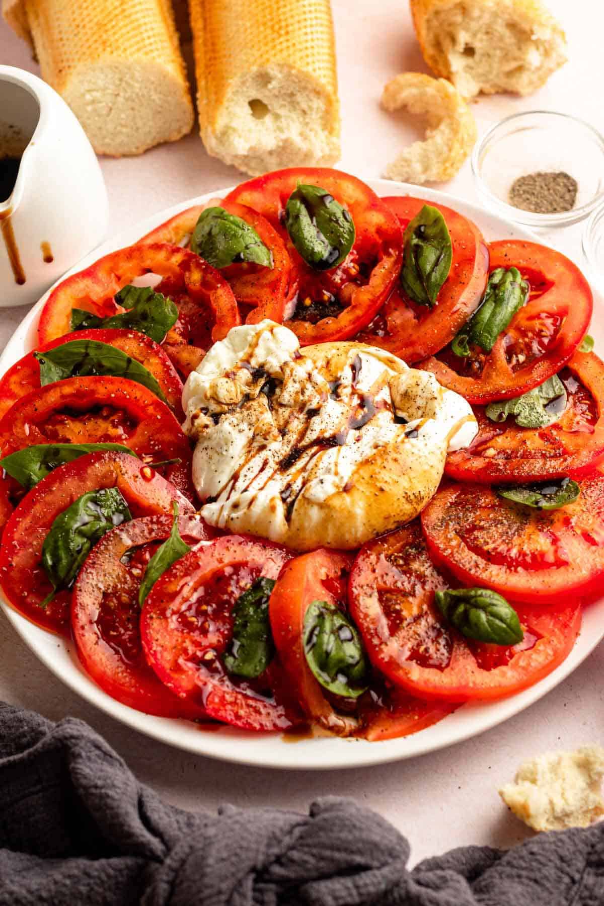 tomatoes arranged on a plate and served with basil and burrata cheese.