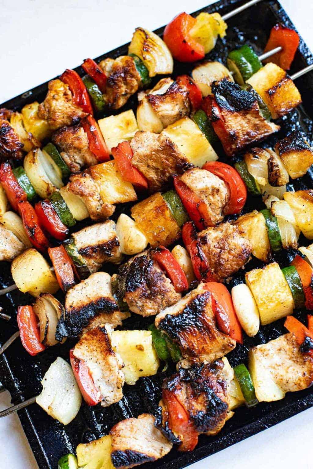 chicken kabobs with pineapples on skewers.