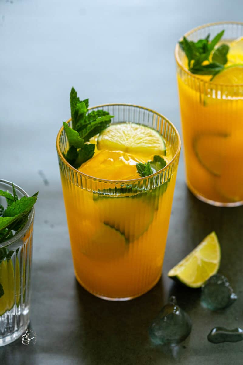 yellow mango mocktail in a tall glass with mint leaves.