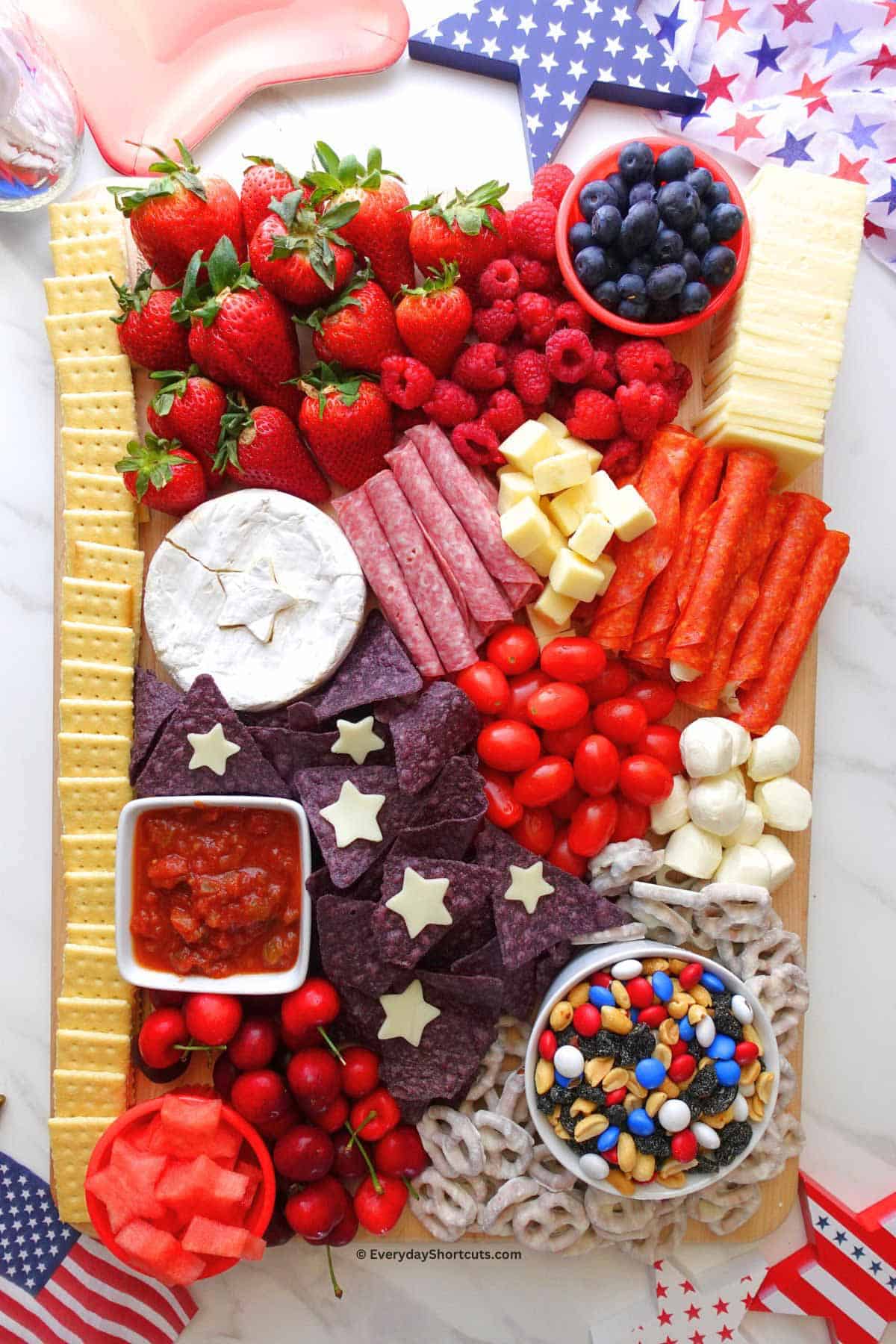 charcuterie board with summer berries, cheese, ham and dips.