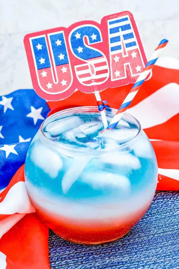 colorful drink with red, white and blue layers and a flag of usa decoration inside.