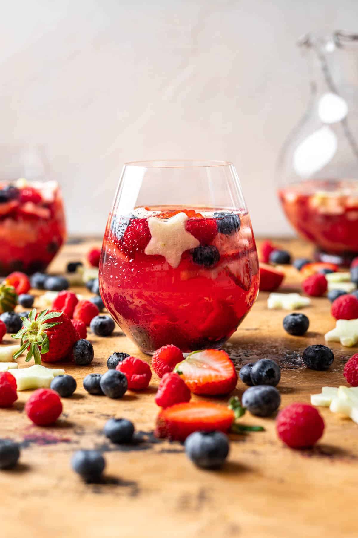 red and white blue sangria glasses with star shaped berries inside.