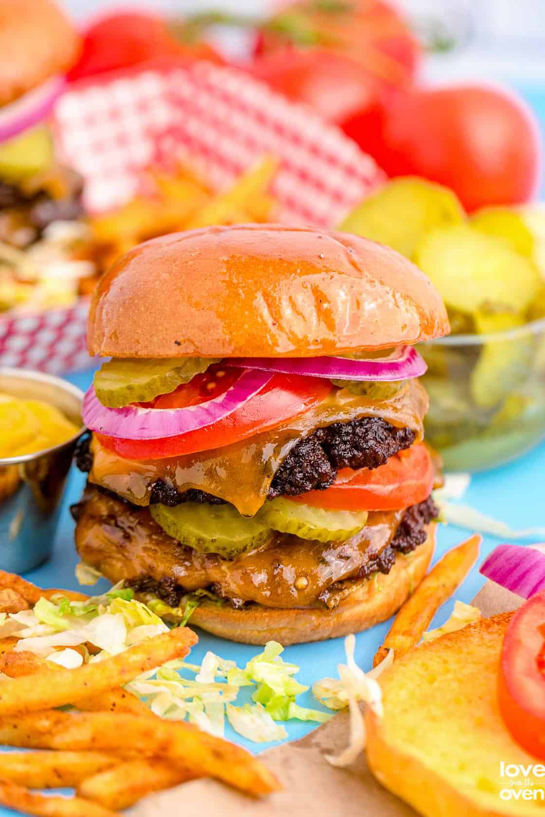 smashburger with red onion and other toppings with a festive background.