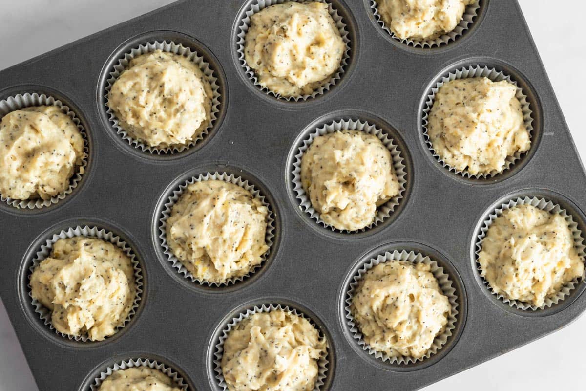 lemon muffin batter in muffin liners in baking pan.