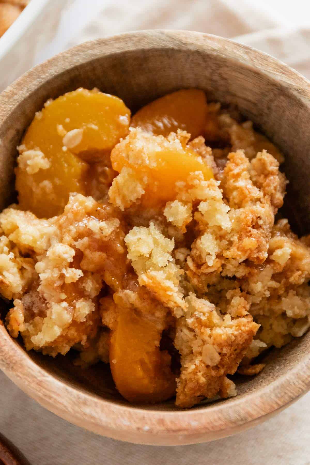 peach cobbler with canned peaches in a wooden bowl.