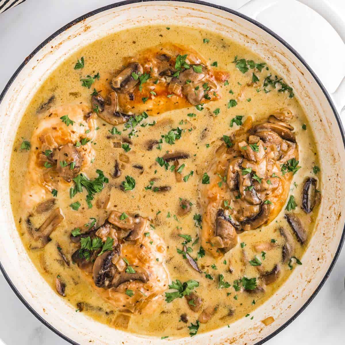 a finished skillet of chicken marsala garnished with freshly chopped parsley.