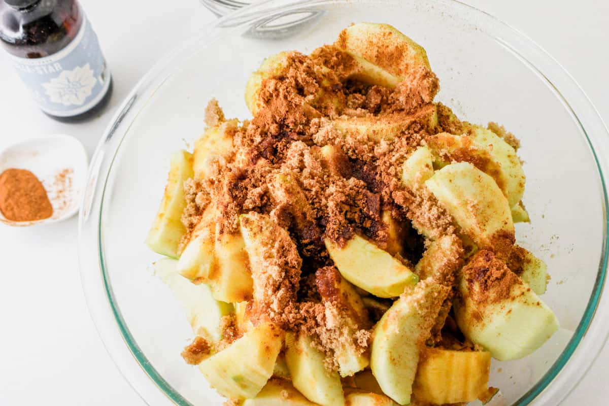 cinnamon sprinkled on apple wedges in a bowl.