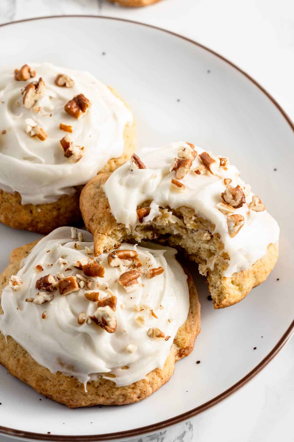 a stack of banana cookies with frosting and pecans.