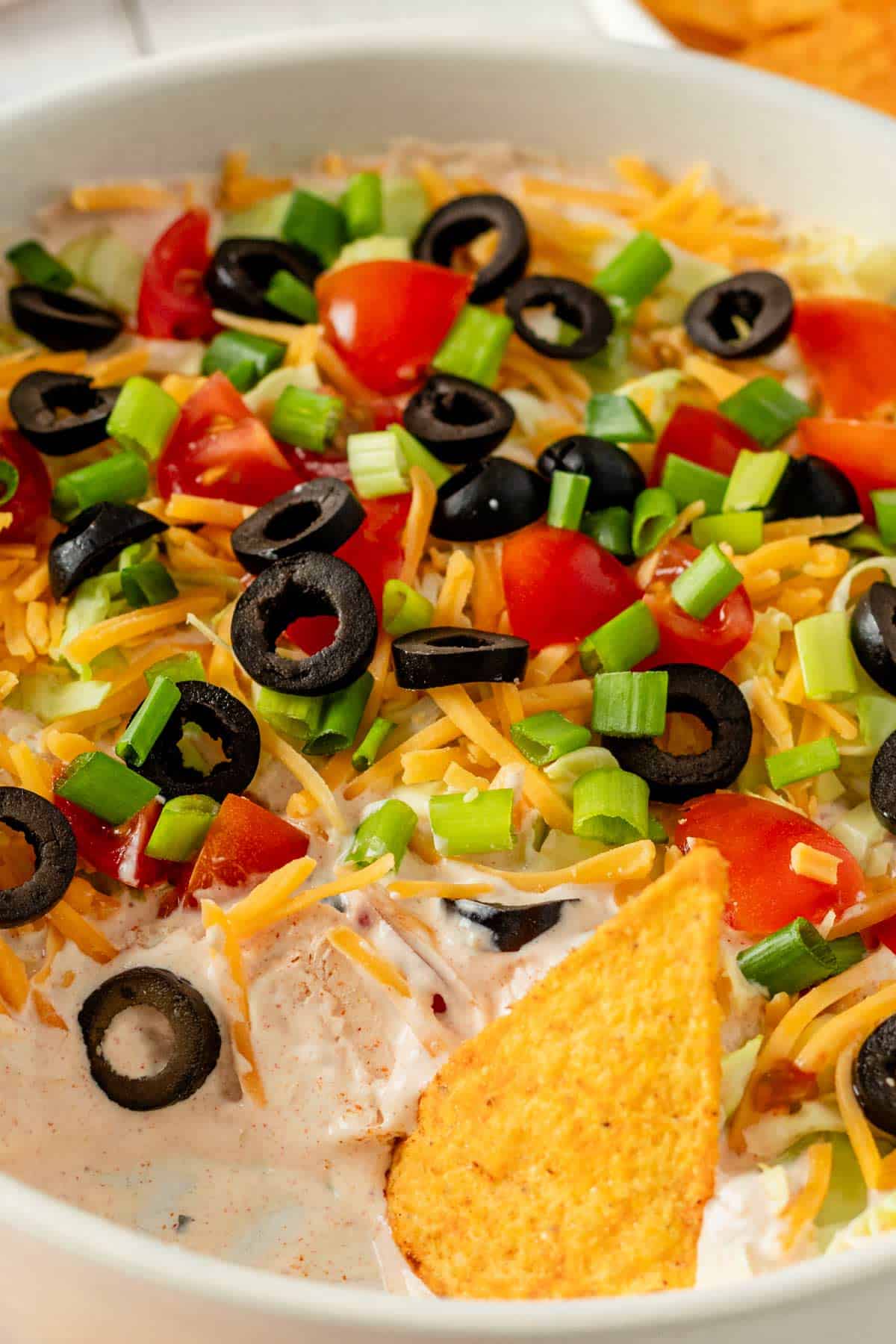 creamy taco dip with toppings and tortilla chips.