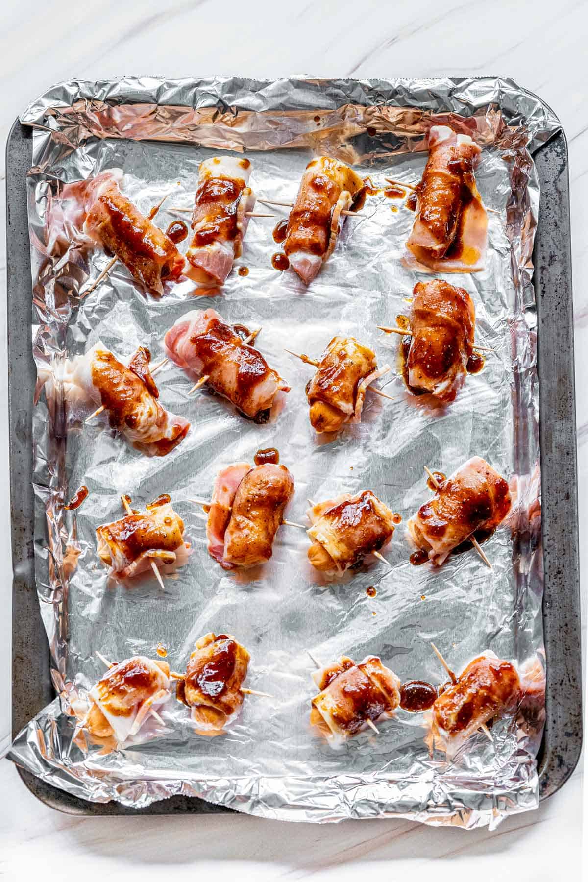 bacon wrapped lil smokies on baking sheet.