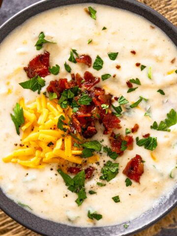 a bowl of creamy chunky potato soup with toppings.