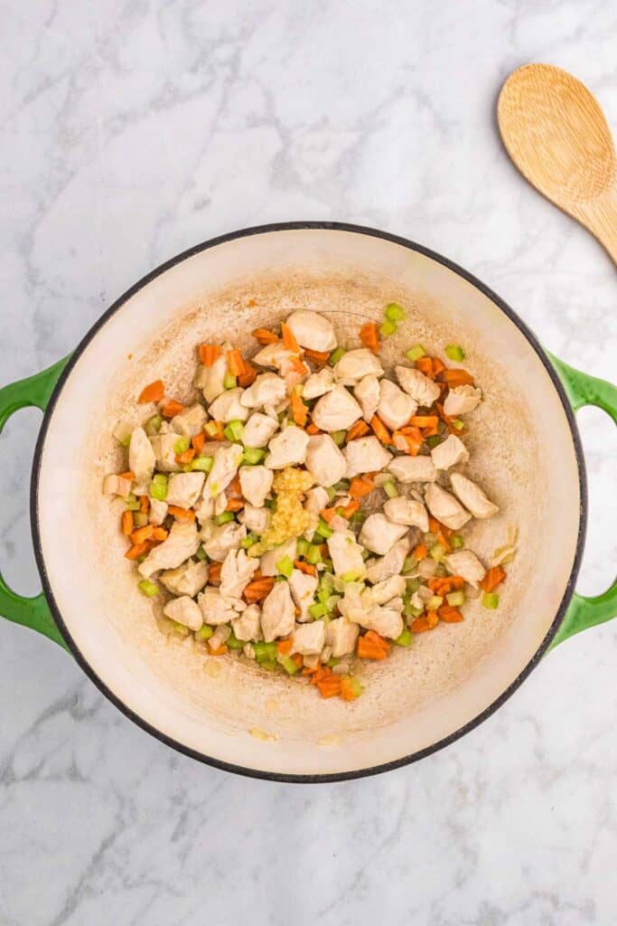 sauteing chicken and vegetables in a pot.