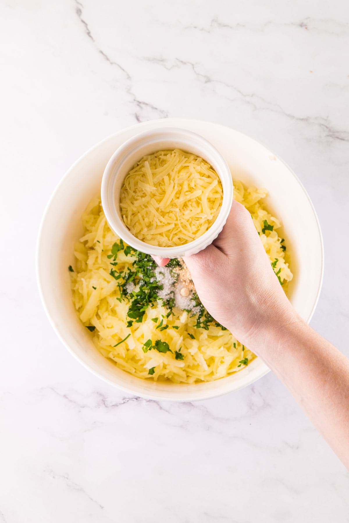 adding parmesan cheese to tater tot batter.