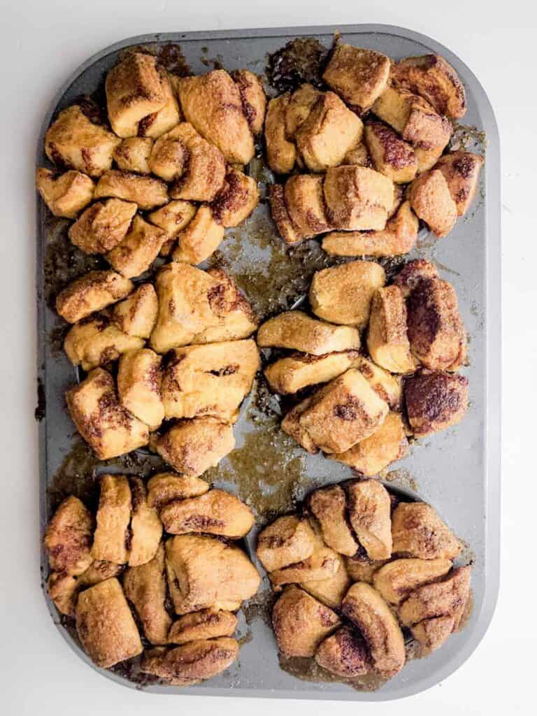 baked cinnamon roll pieces in muffin tin.