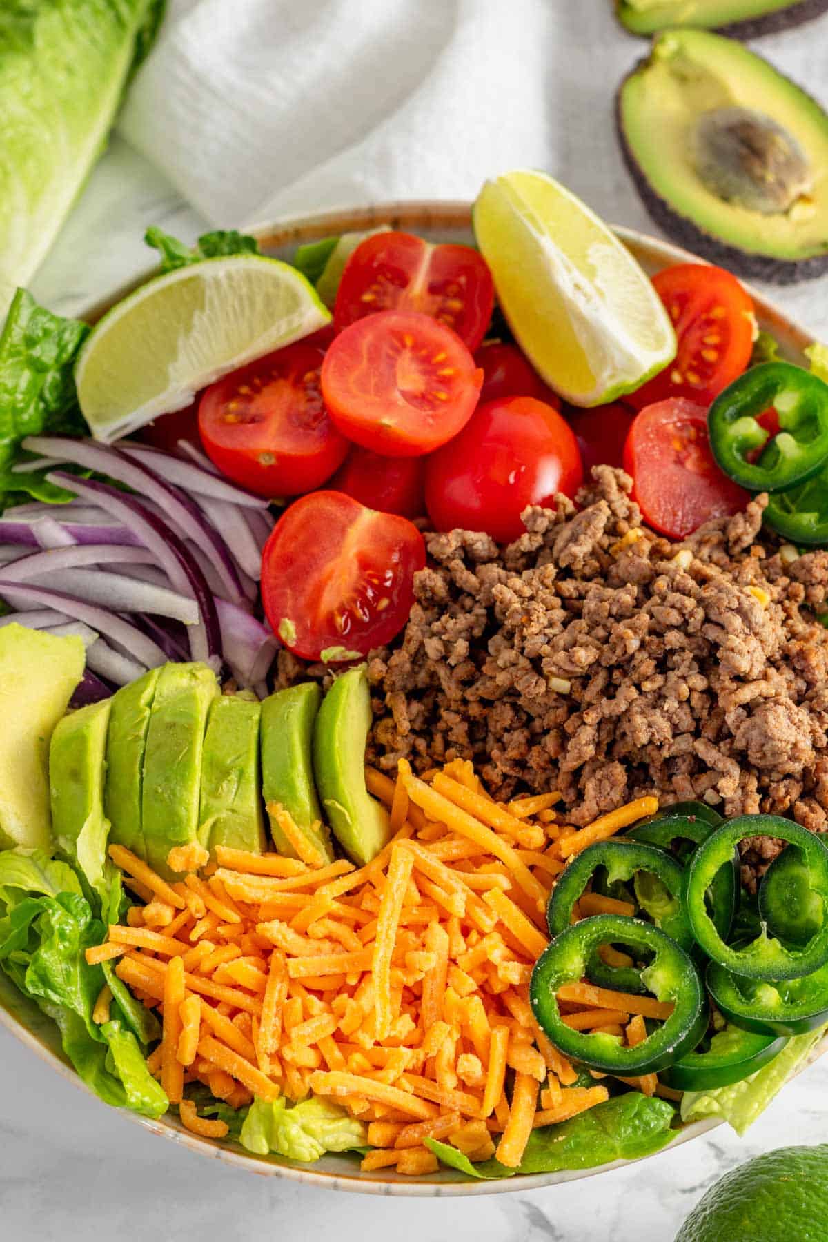 ground beef, tomatoes, avocado and other veggies in a bowl.