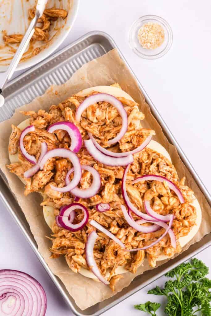 hawaiian buns topped with cheese slices and shredded bbq chicken.