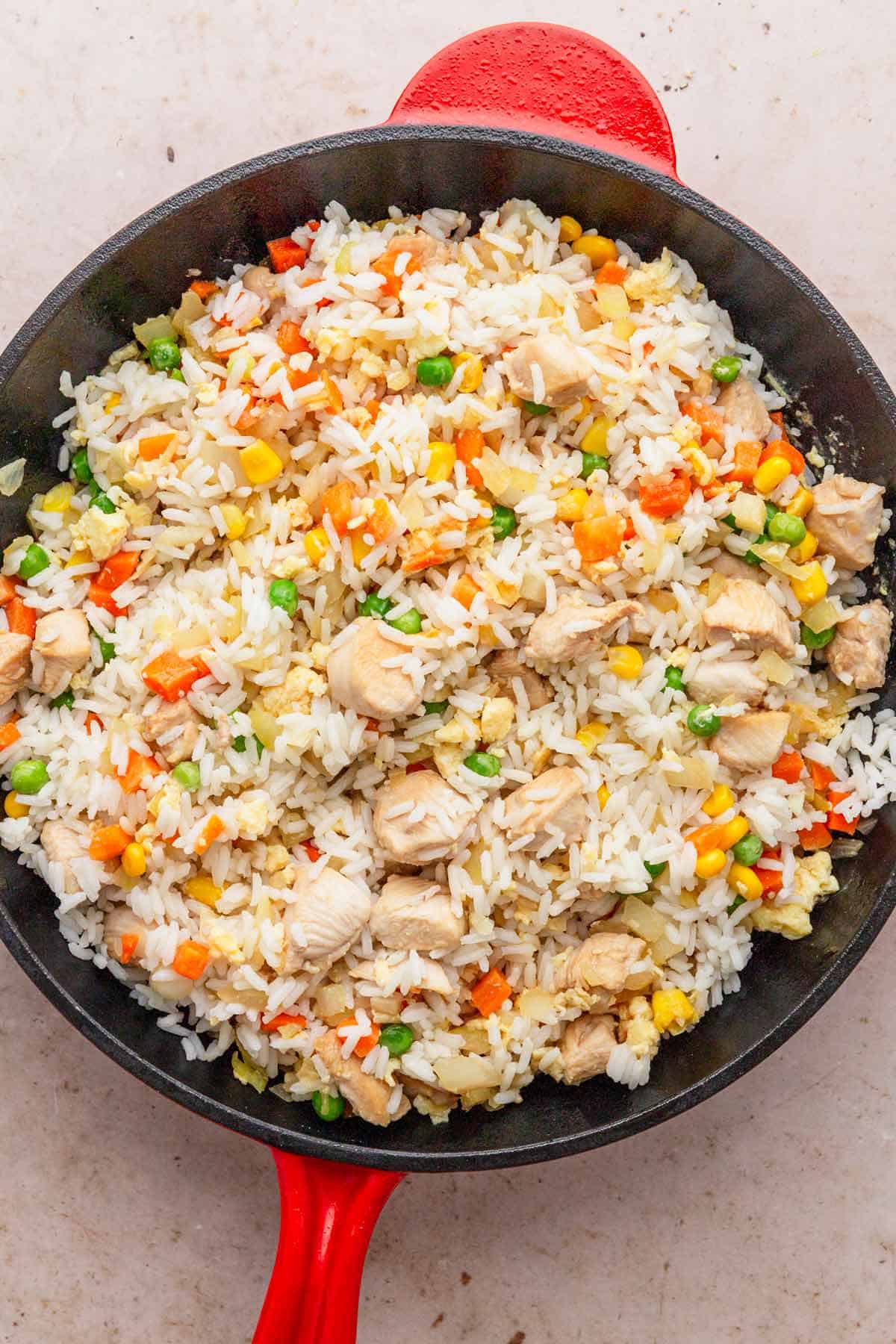 rice in skillet with veggies and chicken.