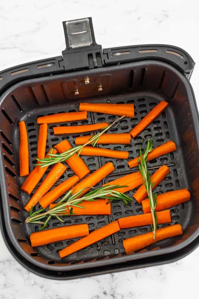 carrot fries in air fryer basket before roasting.