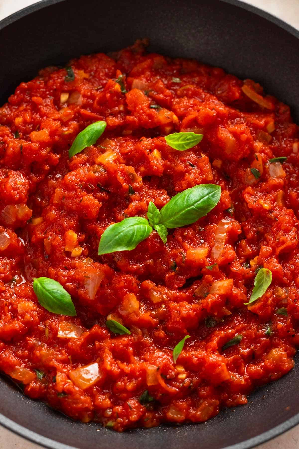 marinara sauce in skillet with fresh basil.