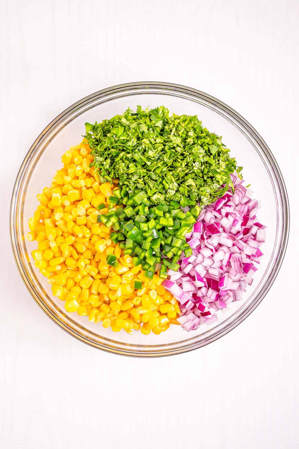 Unmixed corn salsa ingredients with corn, cilantro, and red onion ready to toss.