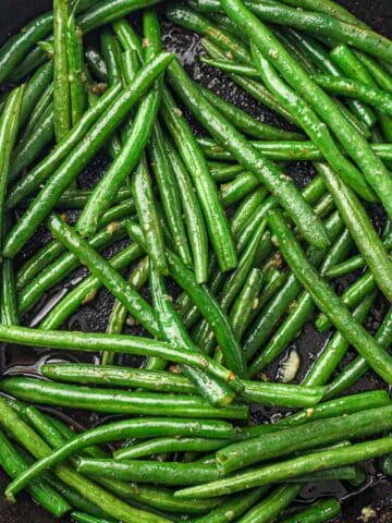 Green beans cooking in a pan, turning bright green.