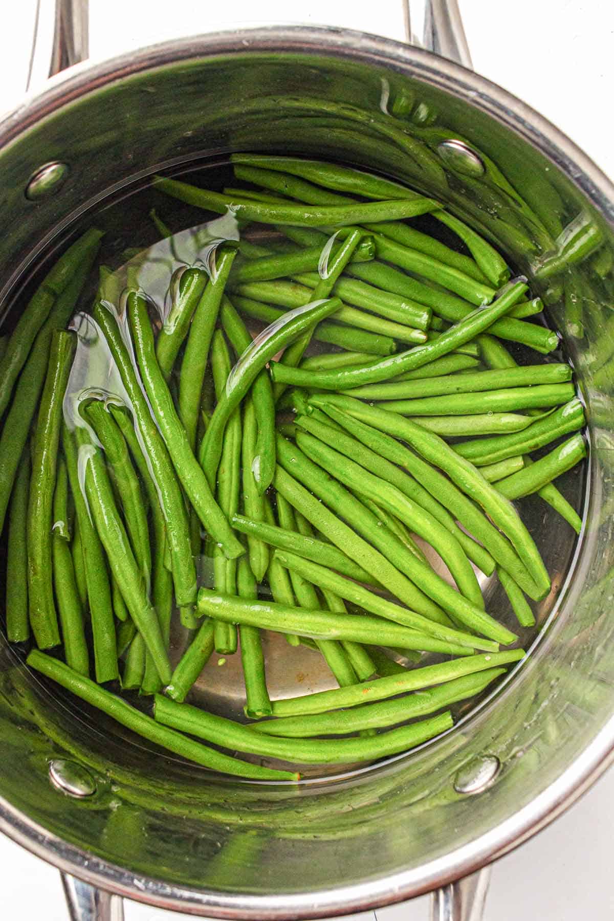 Green beans blanching in a pot of boiling water.