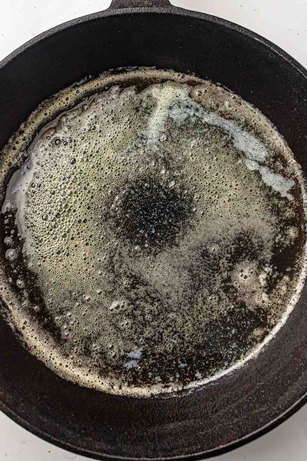 Minced garlic added to melted butter in a skillet.