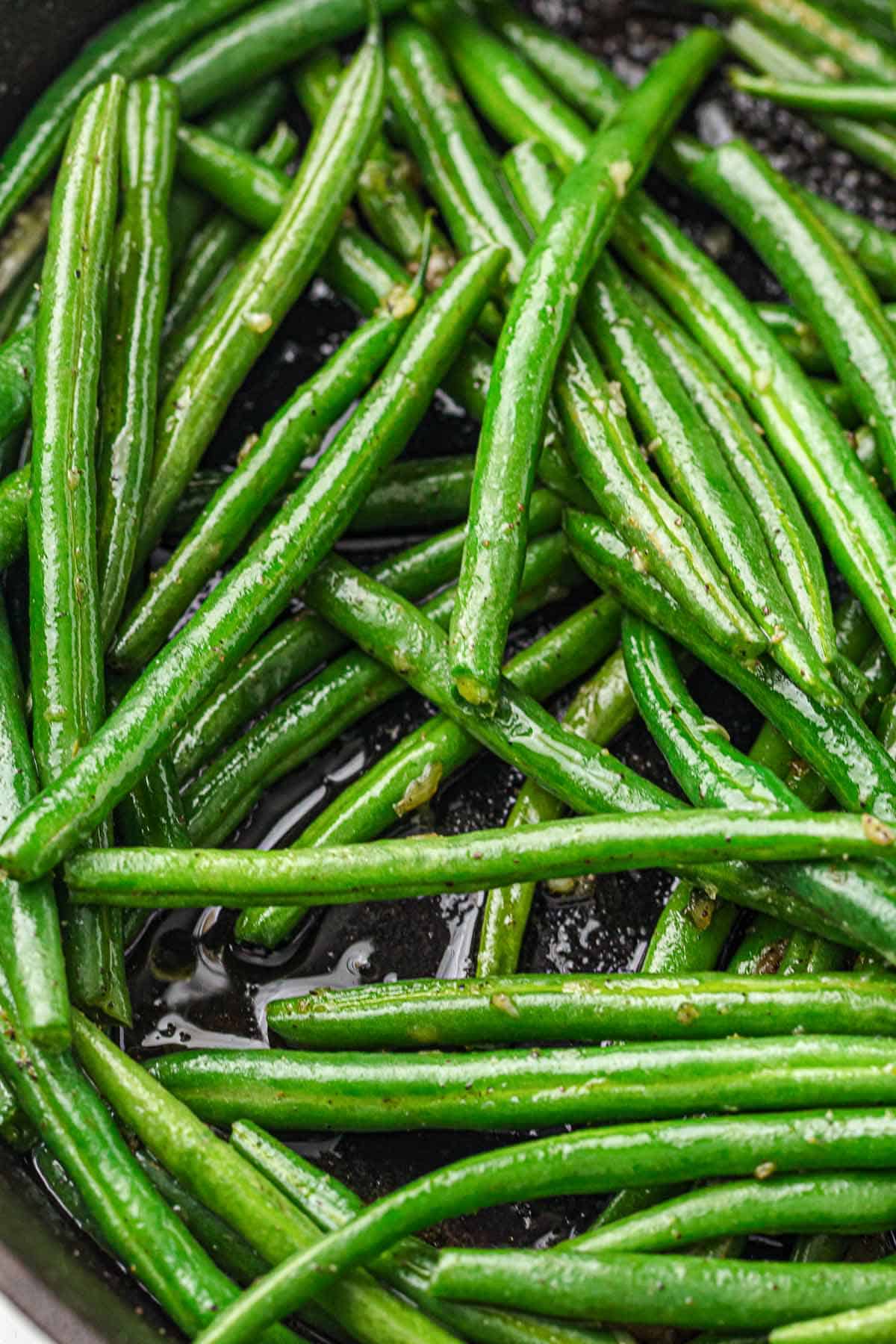 Fresh green beans spread out in a skillet before sautéing.