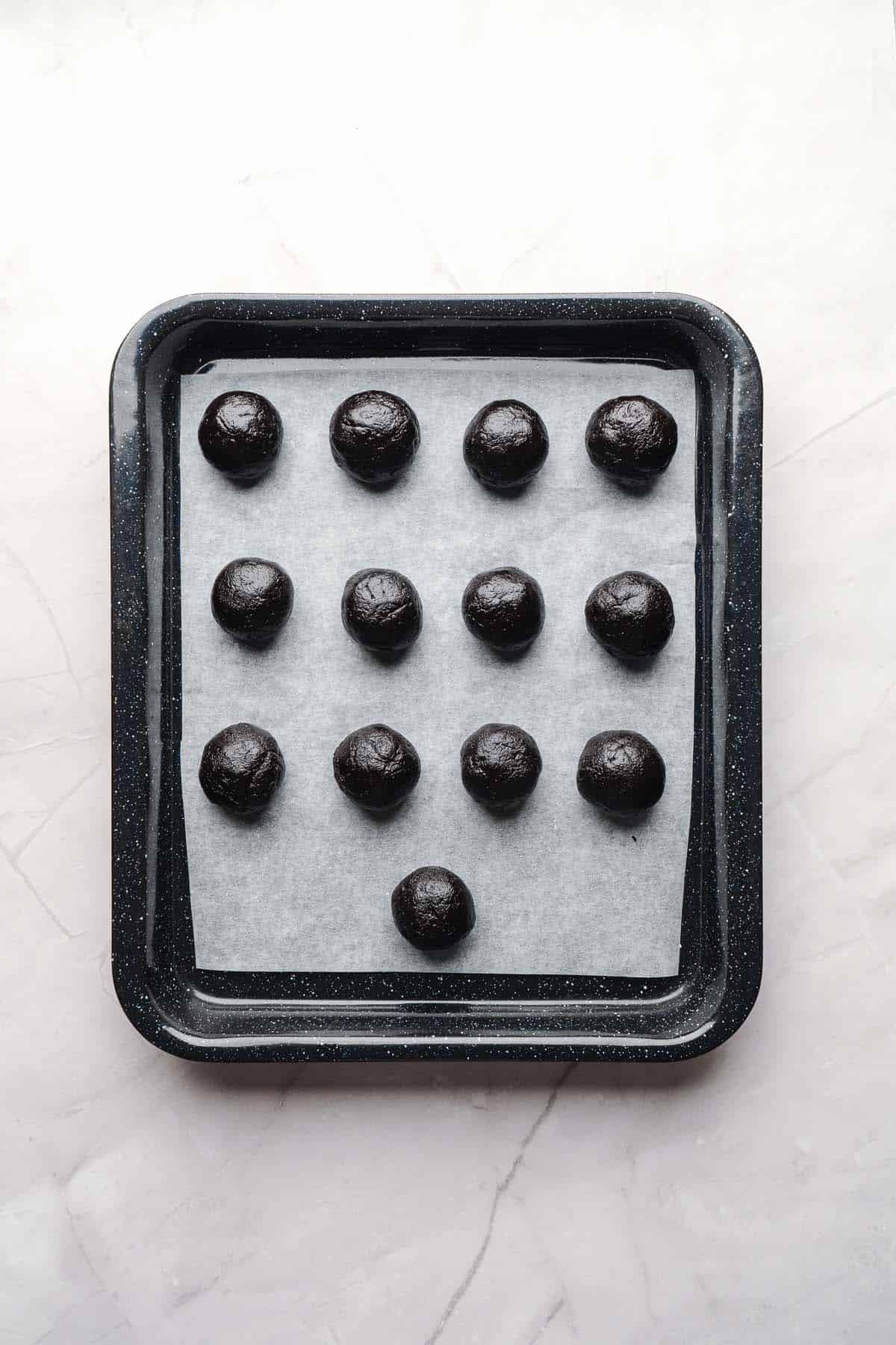 Rolled Oreo balls arranged on a lined baking tray.