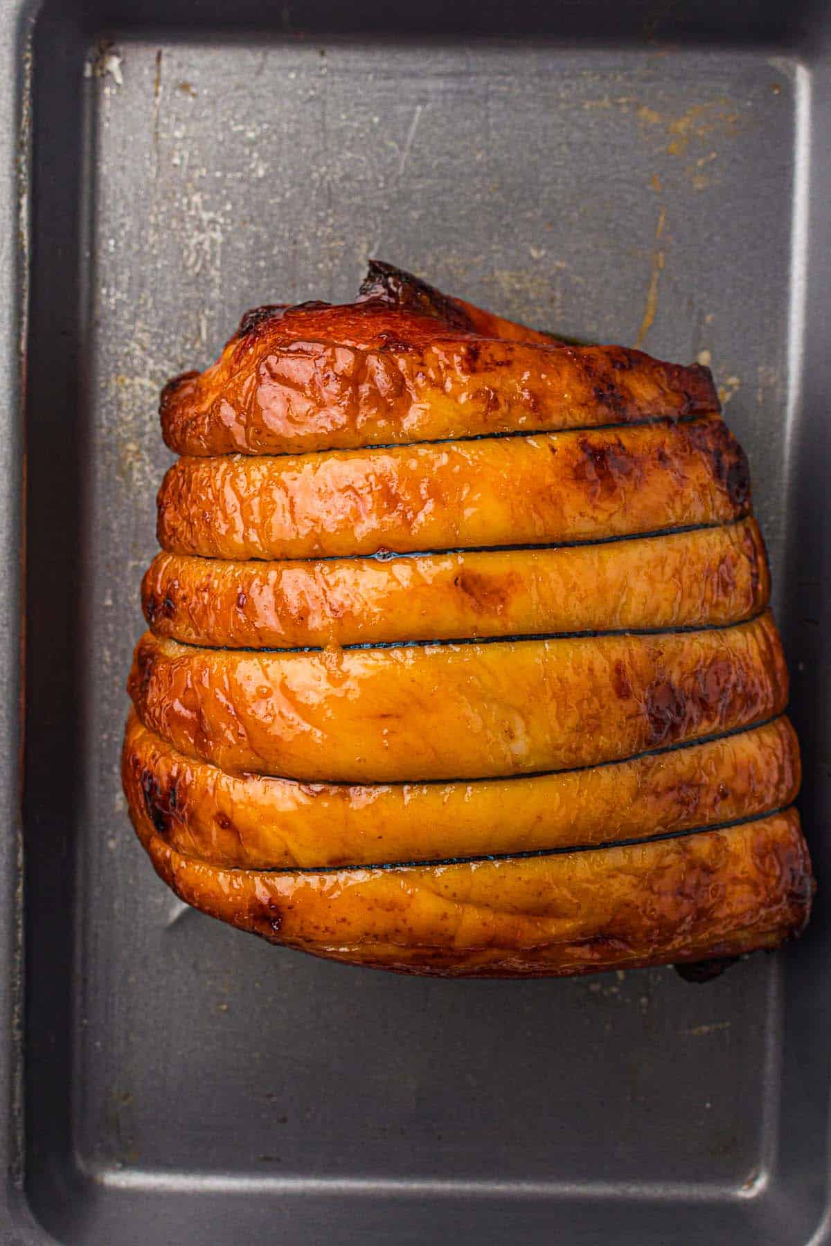 Glazed ham baked in a roasting tray with caramelized surface.