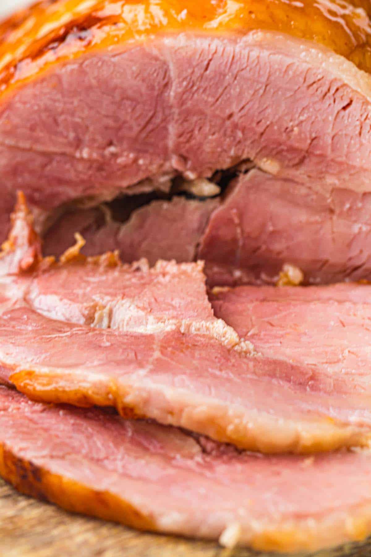 Close-up of sliced honey glazed ham showing pink meat and browned edges.