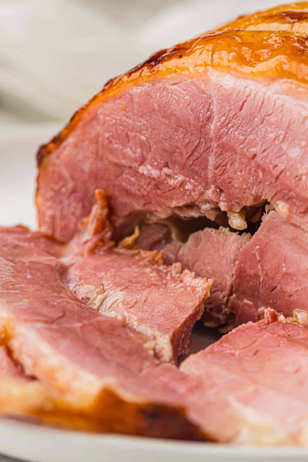 Close-up of honey glazed ham with pink slices and shiny caramelized surface.