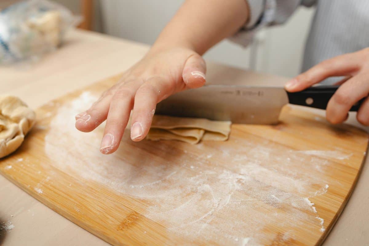 Close-up of Hands Preparing Fresh Pasta on Cutting Board